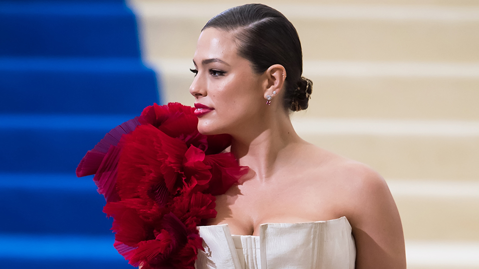 Ashley Graham Style: Ashley wearing a nude-colored gown with a shoulder flower piece at the 2017 Met Gala.