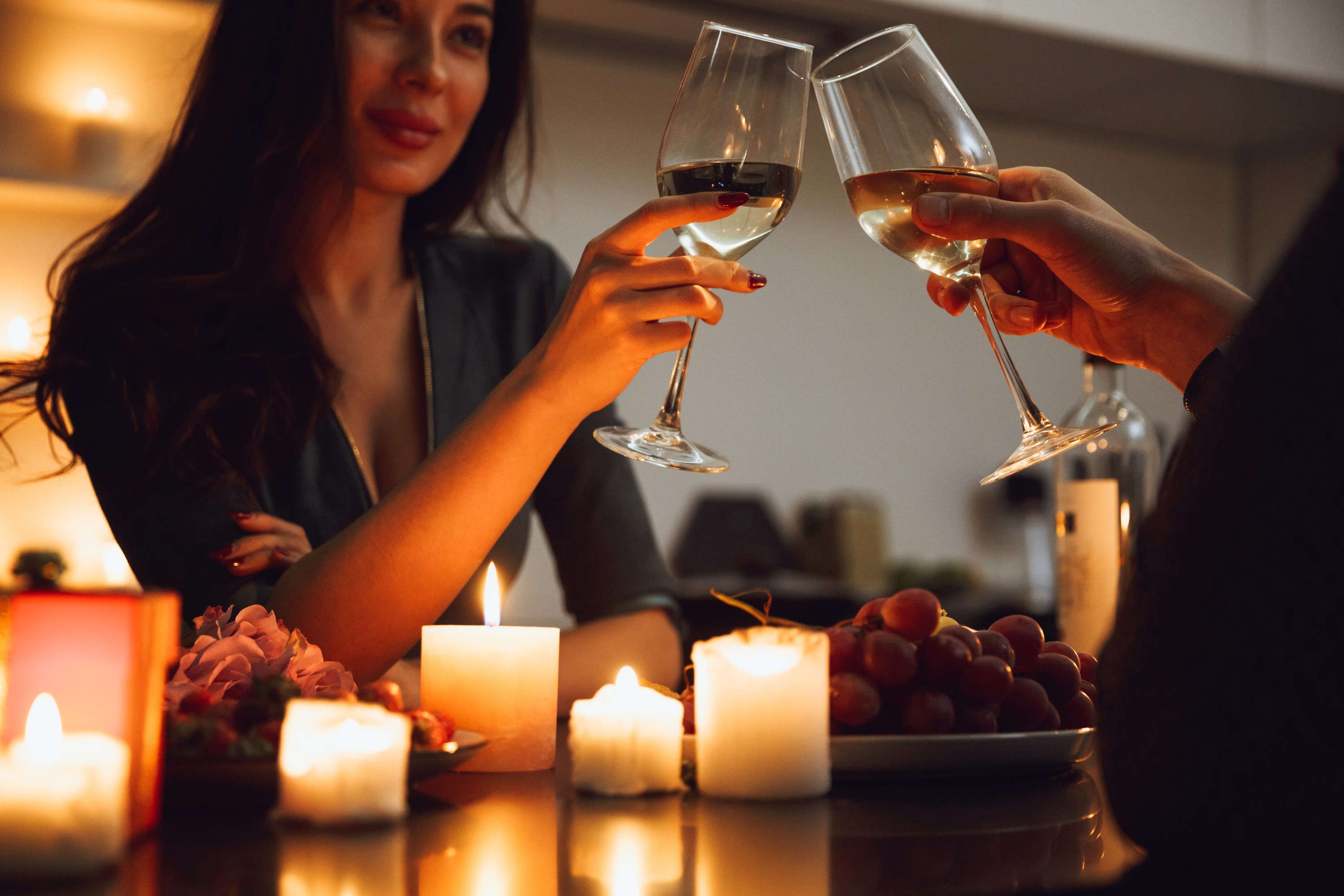 Beautiful passionate couple having a romantic candlelight dinner at home, drinking wine, toasting