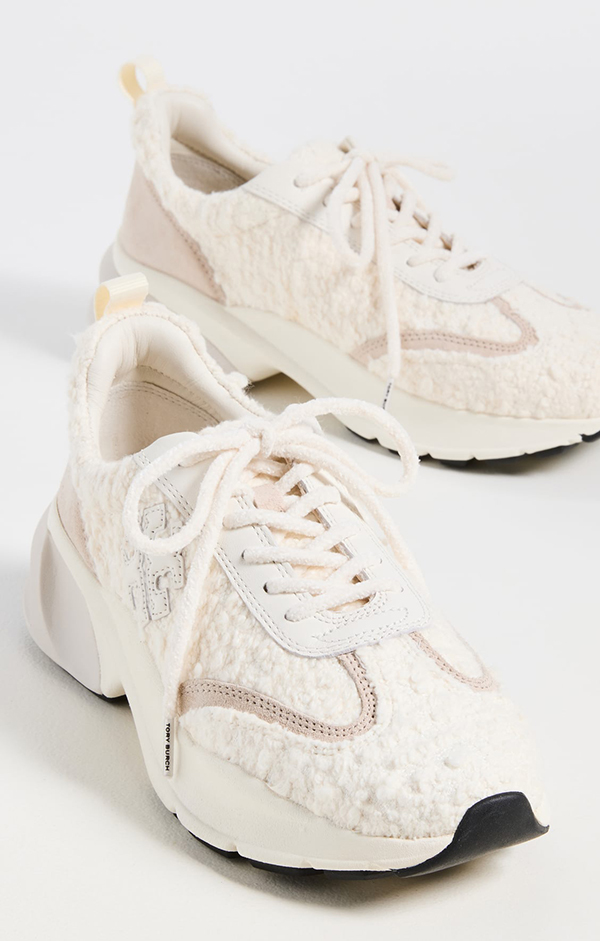 A pair of white sneakers lined with bouclé fabric and designed with fuzzy shoelaces