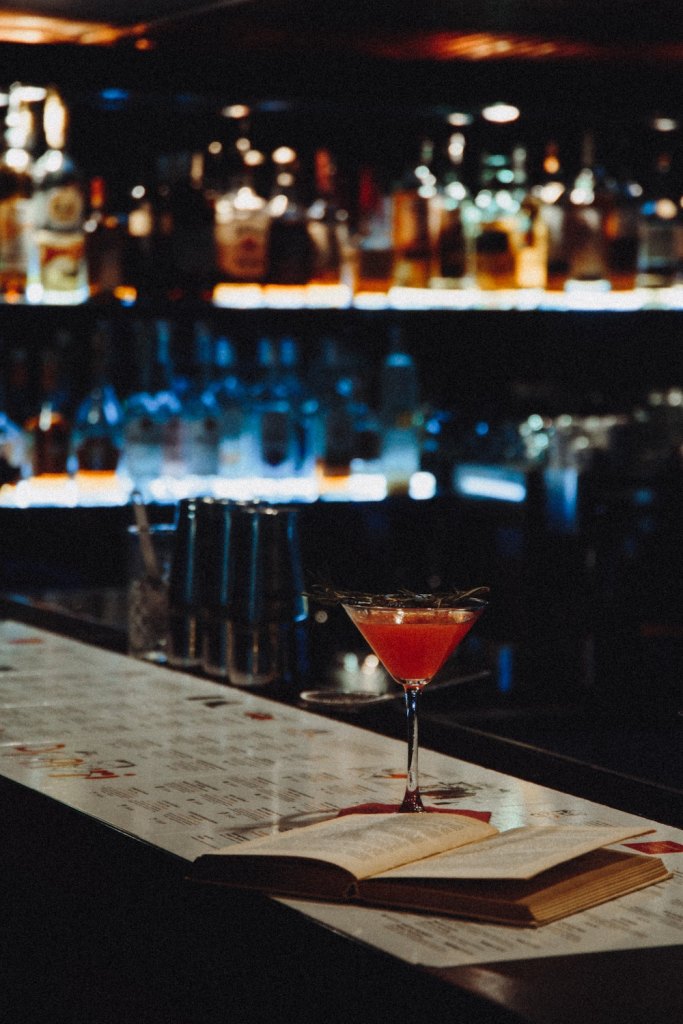 A cocktail on the counter of a dark bar