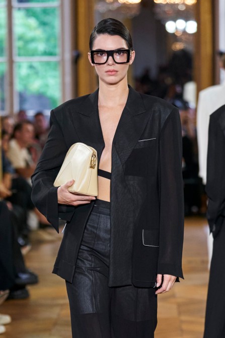 Runway model wearing thick, black, vintage-inspired glasses.