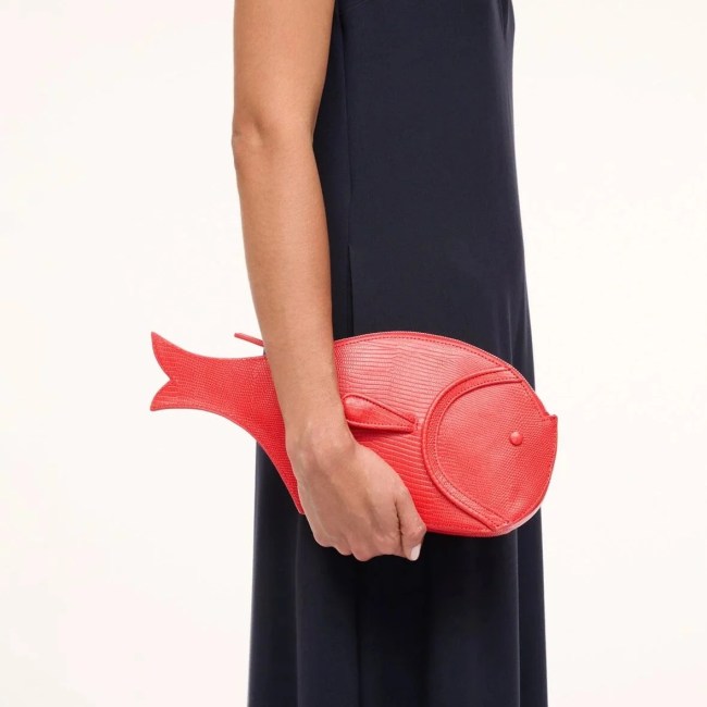 A model holding a red leather fish clutch