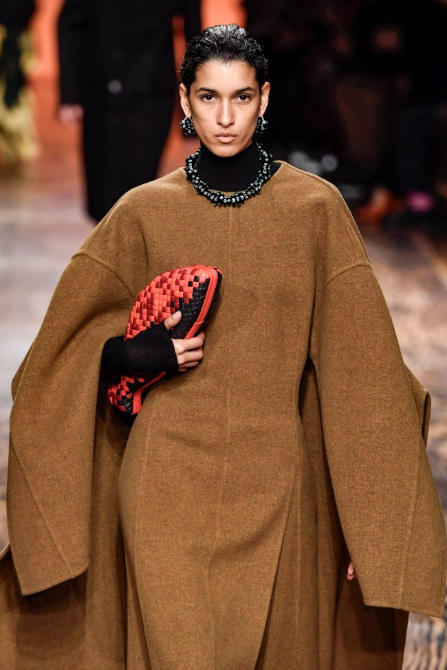 A model carries a woven leather fish clutch at the Bottega Veneta AW 2024 show in Milan.