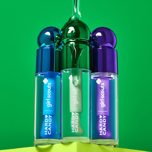 Three tubes of Hard Candy x Girl Scouts Sweet Treat Lip Repair Oil with liquid pouring over them