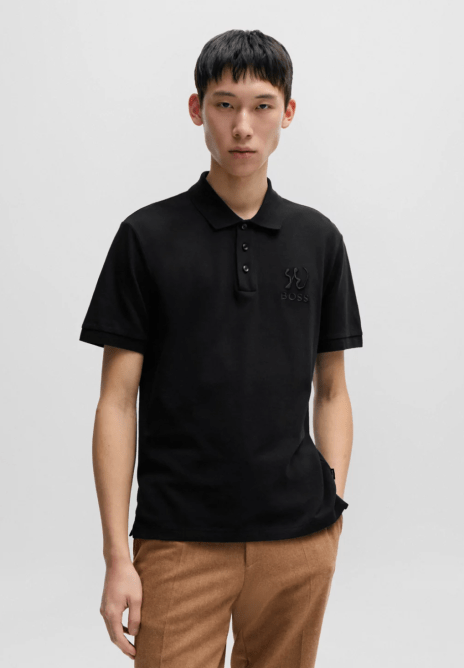 A model wearing a black Hugo Boss polo shirt embossed with calligraphy
