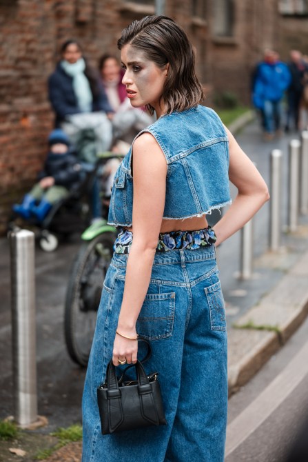 Carlotta Bertotti wears black flower print crop top with matching underwear, denim vest and matching jeans, black bag, outside Philosophy, during the Milan Fashion Week - Womenswear Fall/Winter 2024-2025 on February 23, 2024 in Milan, Italy.