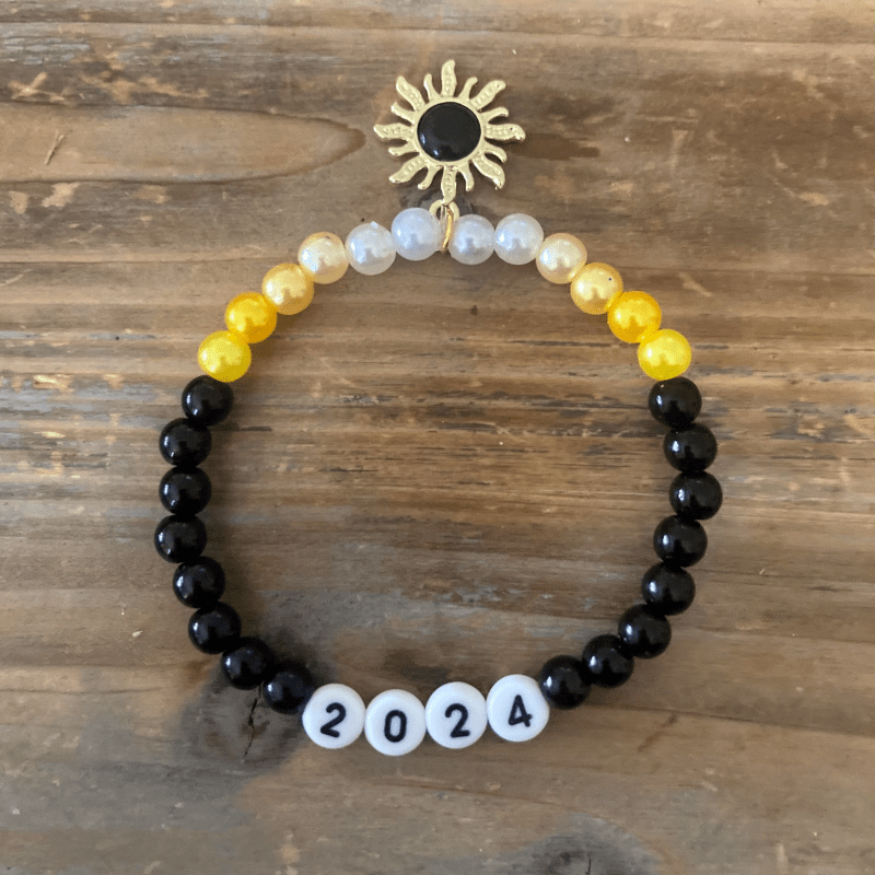A stack of friendship bracelets with colorful beads and beads that spell "Eclipse 24"