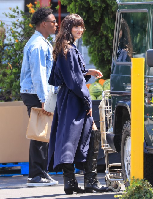 Dakota Johnson wearing a navy trench coat and leather moto boots.