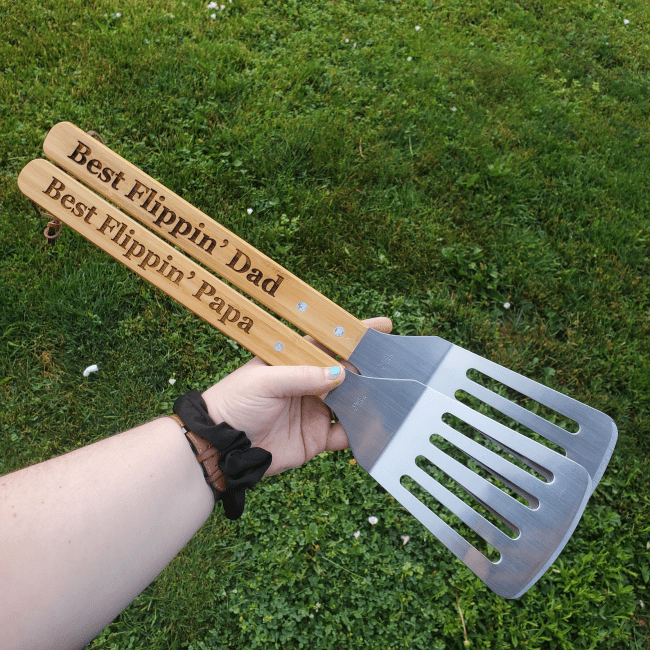 Two BBQ spatulas that say "Best Flippin' Dad" and "Best Flippin' Papa" on the handles