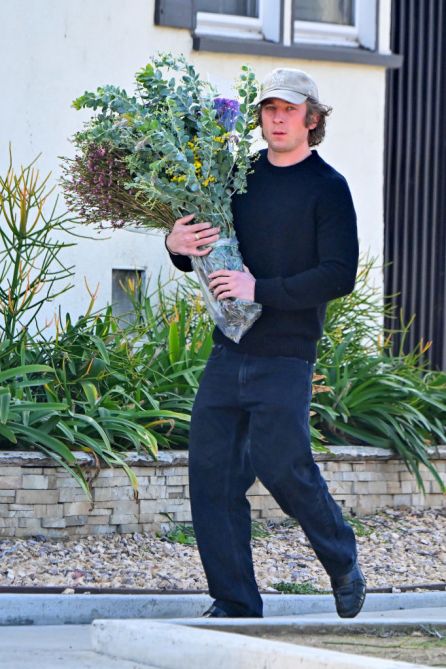 Jeremy Allen White, black sweater, jeans, flowers, baseball cap