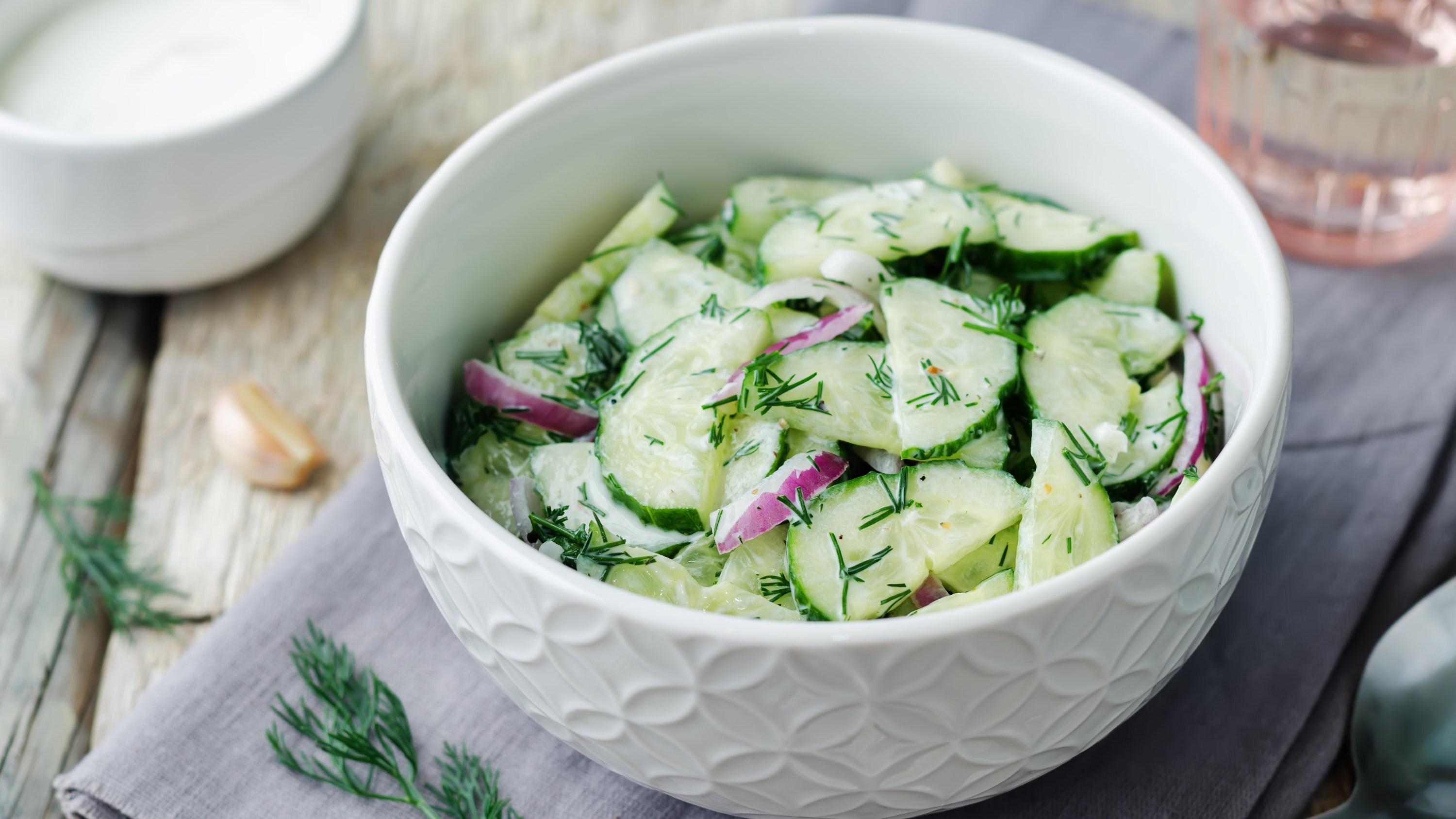 A bowl of cucumber salad with dill and red onion