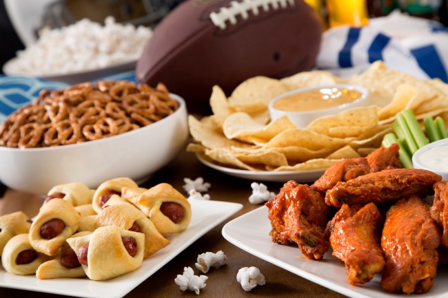 Hot wings, nachos, pigs in a blanket, beer, and popcorn, a tailgate party spread