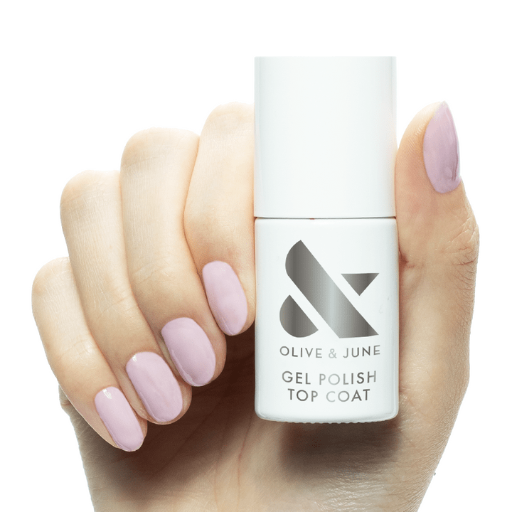 A hand model with light pink nails holding the Olive & June Gel Polish Top Coat