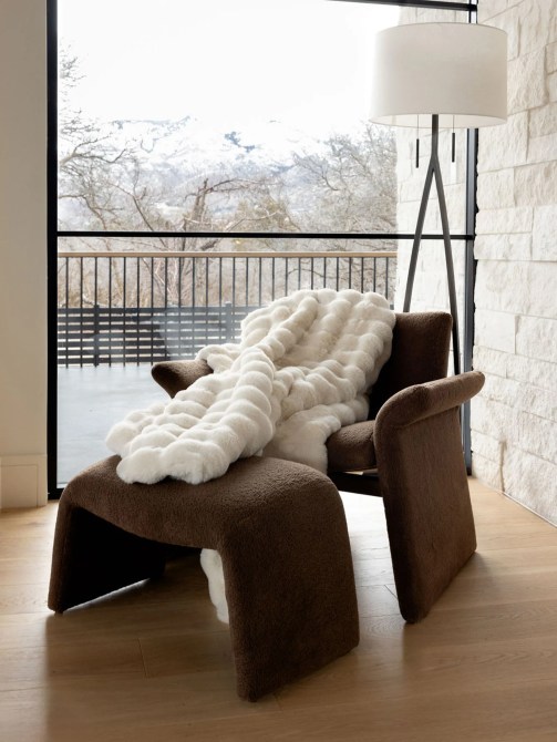 A white, textured blanket atop a brown chair and ottoman