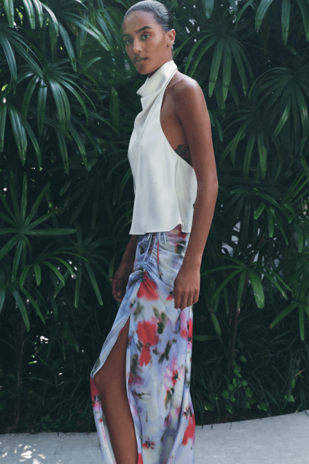 A model wearing the Zara Satin Effect Halter Top in white with a colorful floral skirt