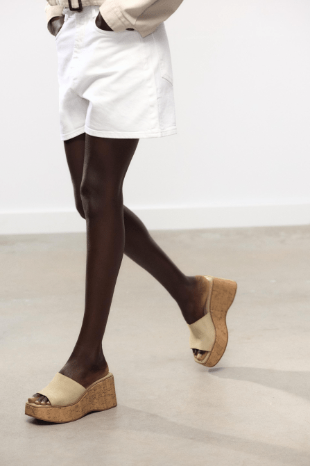 A model walking and wearing the Zara Suede Platform Wedges in light beige